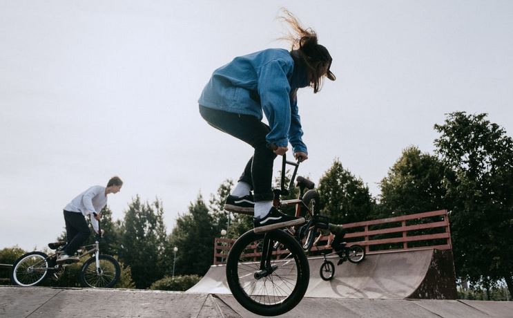 3 personnes qui font du freestyle en BMX dans un skate park