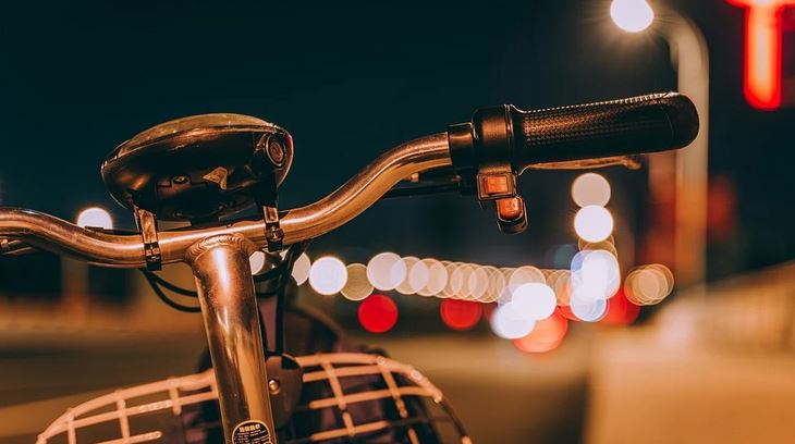 photo du guidon dun velo de ville avec les lumieres dans lampadaires en arriere plan