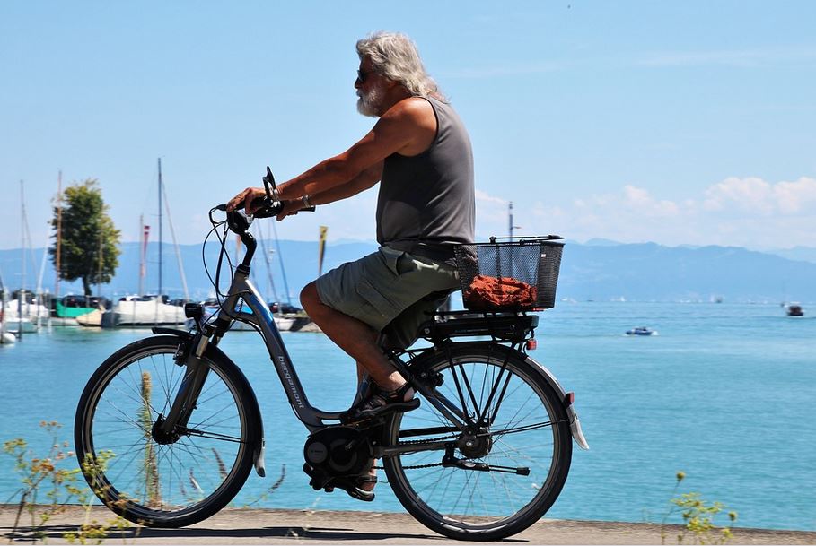 un homme age en marcel faisant du velo electrique pres de la mer