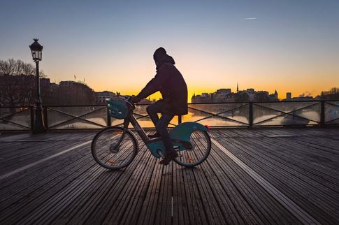 un homme sur un velib a paris roulant sur un pont en regardant le coucher du soleil