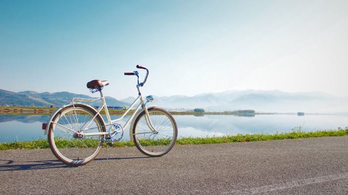 un velo tout chemin ou VTC appuye sur sa bequille sur une route au bord dun lac ensoleille