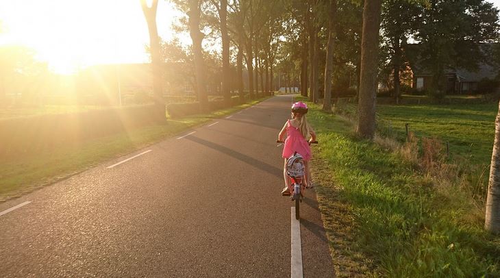 une petite fille qui fait du velo le long de la route