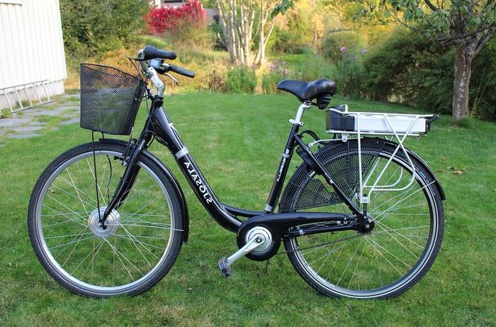 un velo electrique pour femme pose sur la bequille dans un jardin