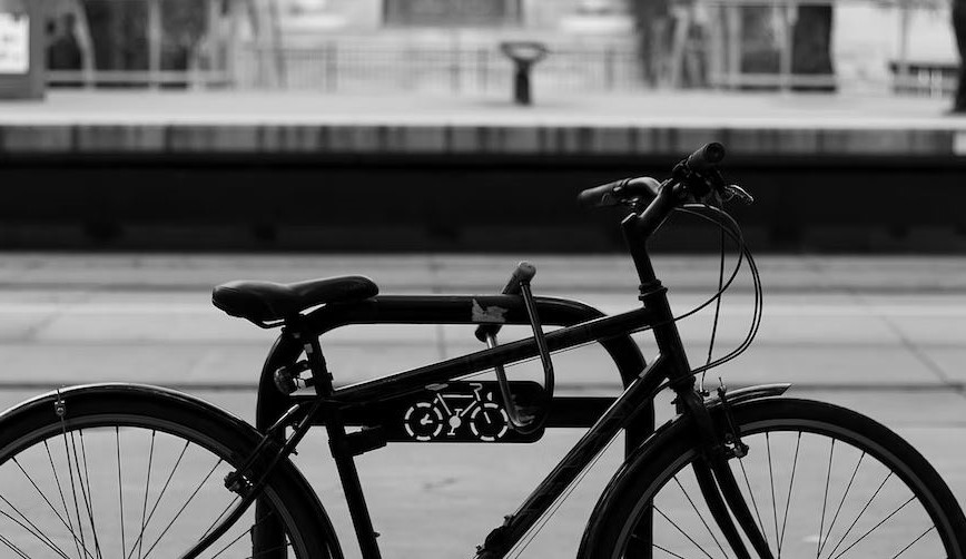 un velo noir dans la rue attache a un emplacement reserve aux velos avec un cadena solide