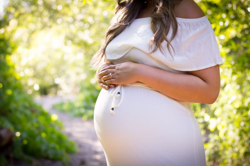 une femme enceinte avec une robe blanche qui se tient debout au milieu dune piste cyclable