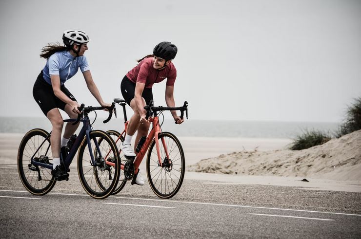 deux femmes cyclistes entrain de faire du velo de route a cote dune plage