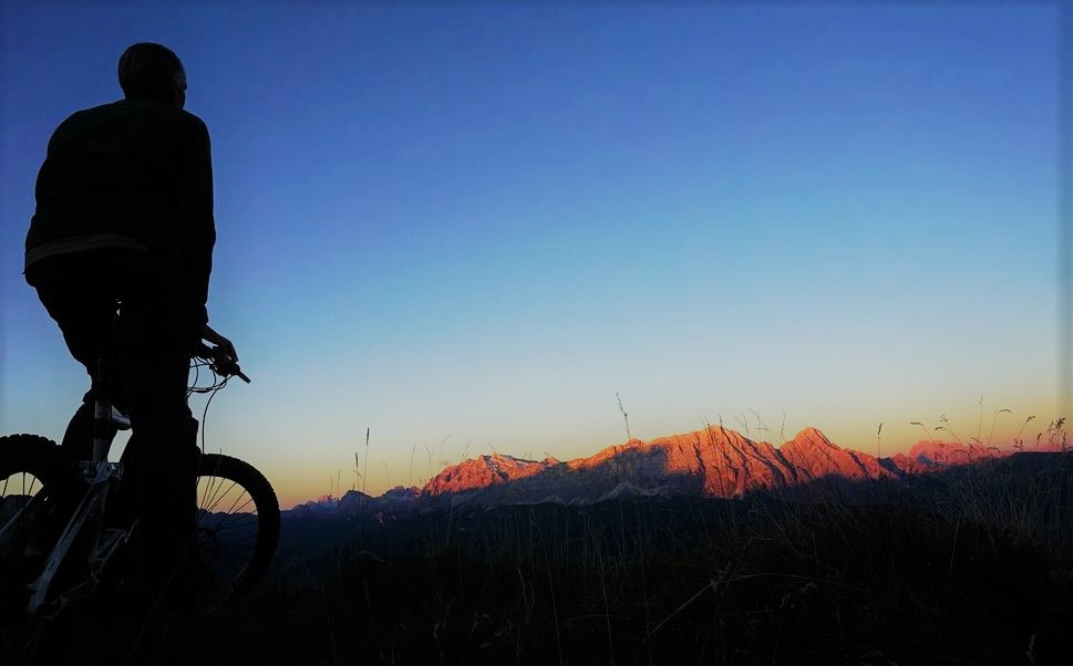 un cycliste en vtt electrique qui admire un couché de soleil sur les montagnes