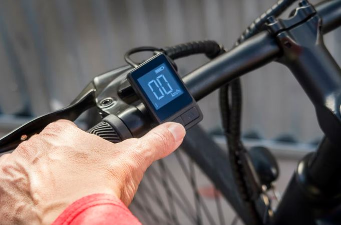 un cycliste qui regle le compteur vitesse de son velo a assistance electrique